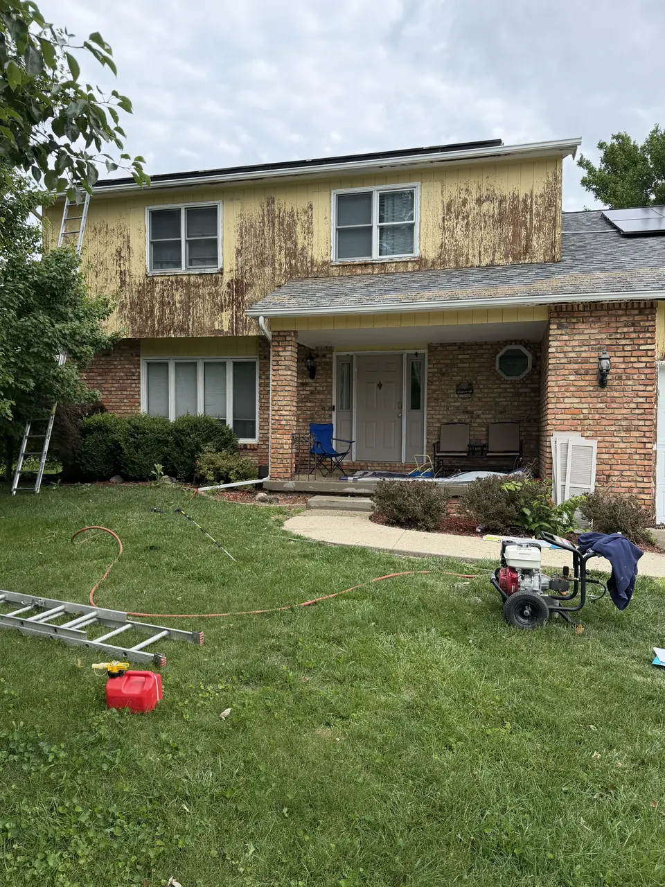 Crew scraping loose paint from a two-story home