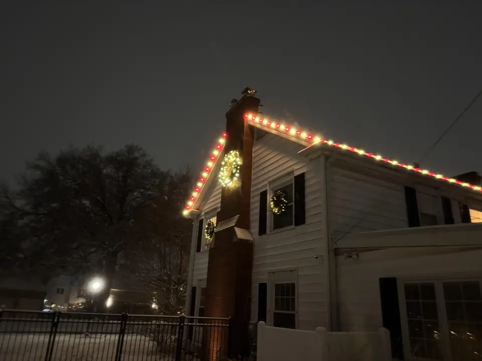 Tall gable and chimney outlined in warm and red lights