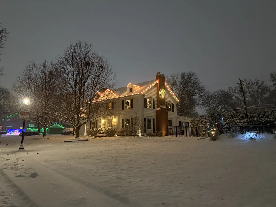 Historic home with roofline lights on a snowy evening