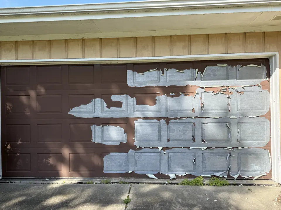 Garage door with large sheets of peeling paint