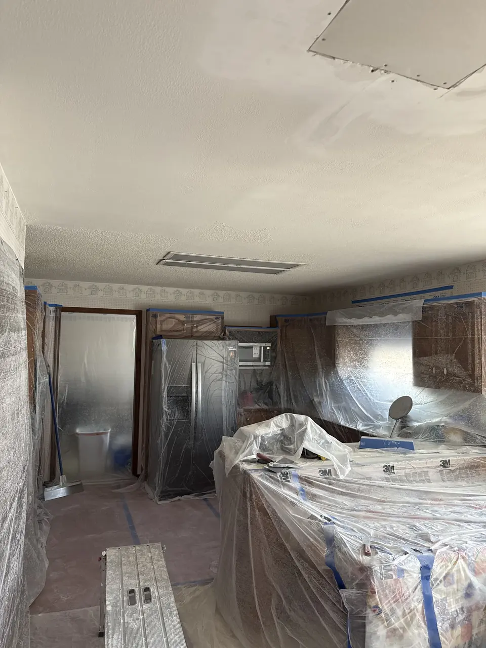 Plastic-covered cabinets and appliances during ceiling work