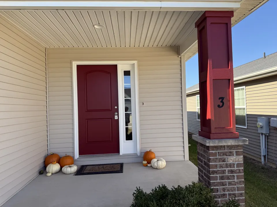 Porch with a red front door and matching red post