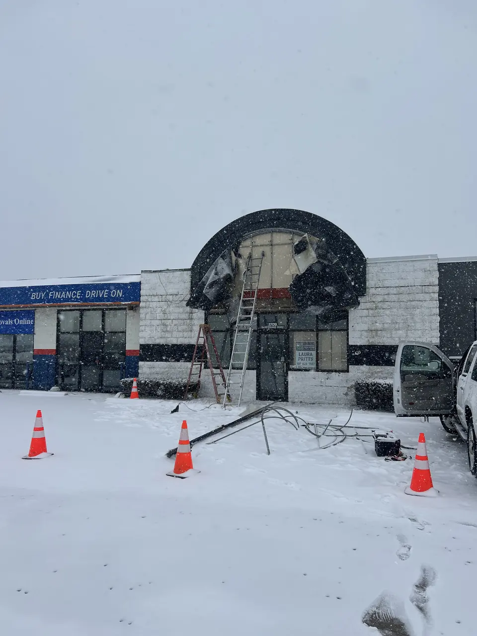 Crew removing an old storefront awning in winter